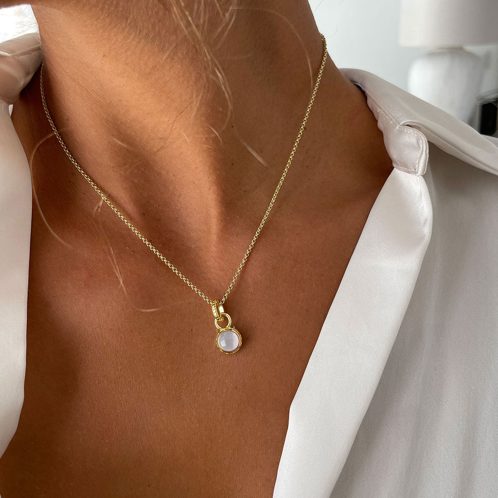 woman in white shirt wearing small mother or pearl stone gold necklace