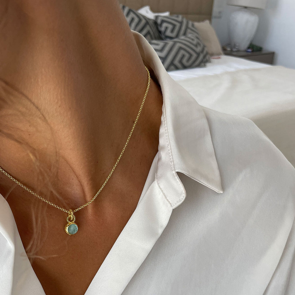 woman in white shirt wearing small aqua stone gold necklace