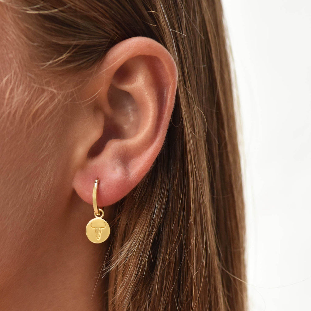 18 kt gold vermeil hoops with coin charm drops engraved with Western style steer heads . Azuni London