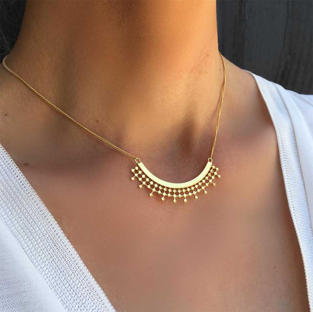 Model wearing gold bead curved pendant necklace, 22 karat yellow gold plate, by Azuni London