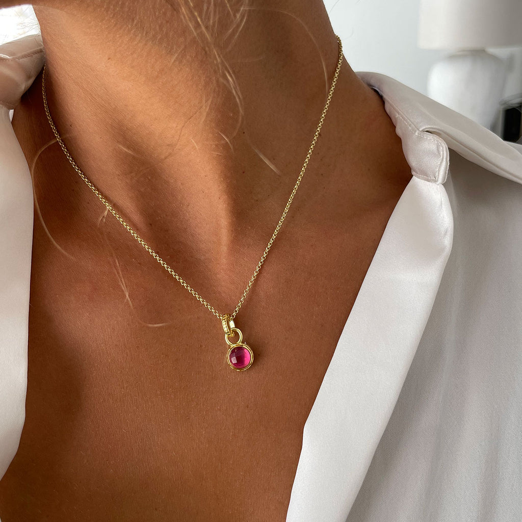 woman in white shirt wearing small red stone gold necklace