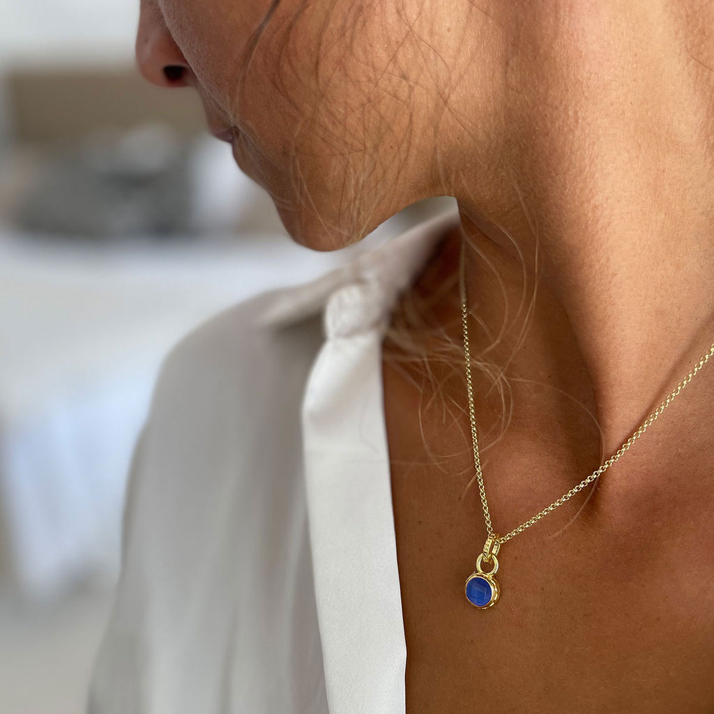 woman in white shirt wearing small lapis stone gold necklace