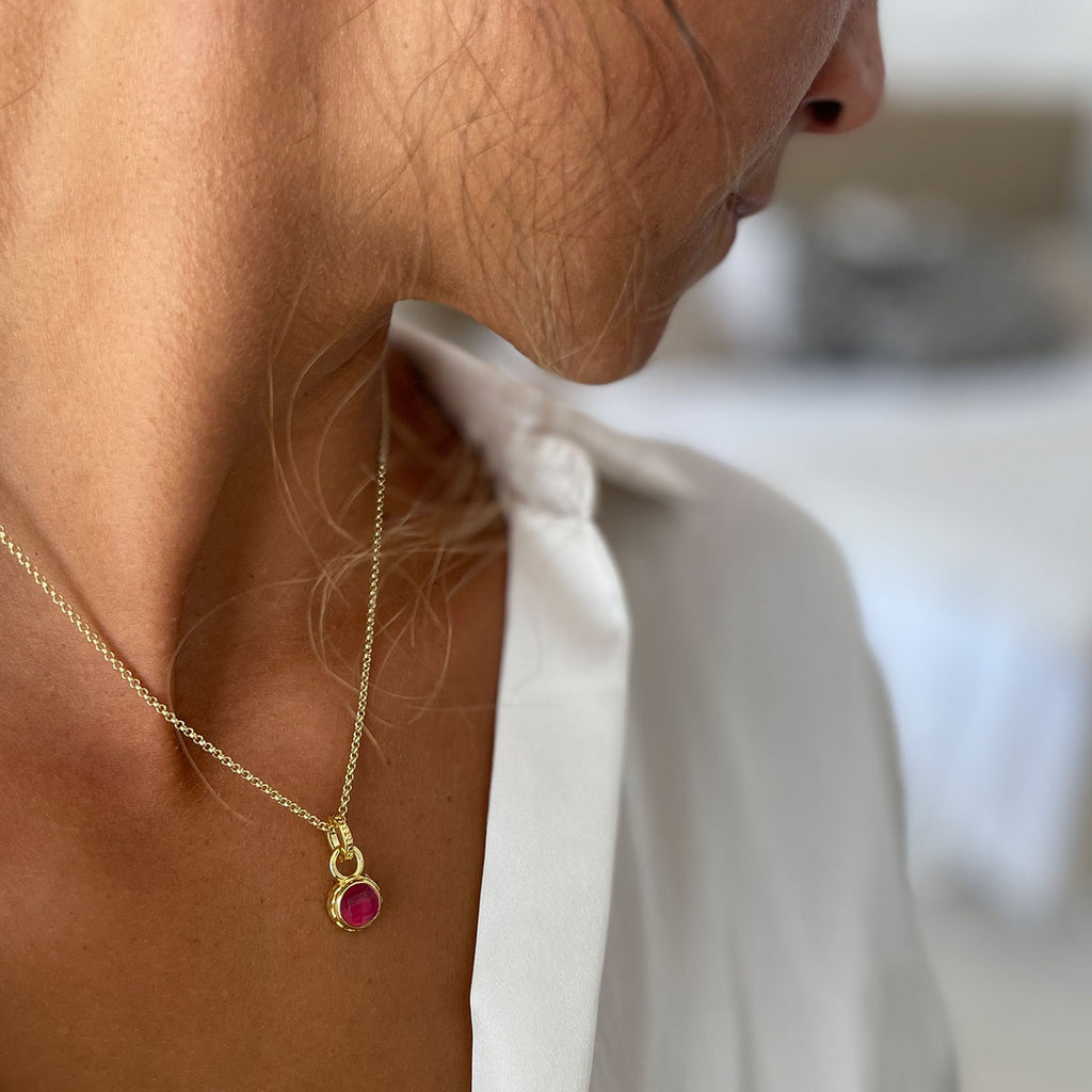 woman in white shirt wearing small red stone gold necklace